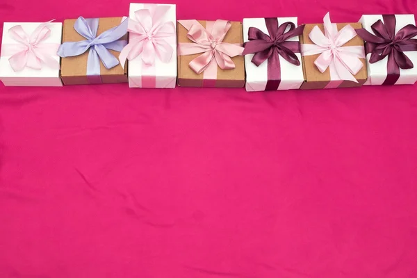 Подарункові коробки прив'язані атласною стрічкою на рожевому фоні . — стокове фото