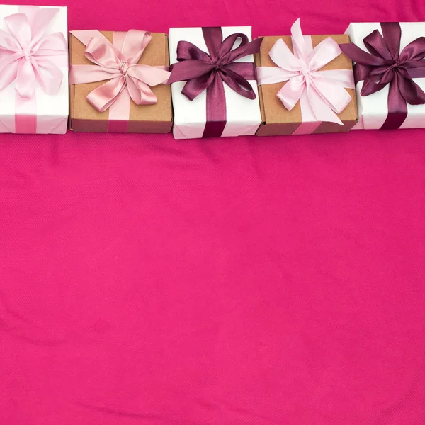 Scatole regalo legate con nastro di colore satinato su sfondo rosa . — Foto Stock