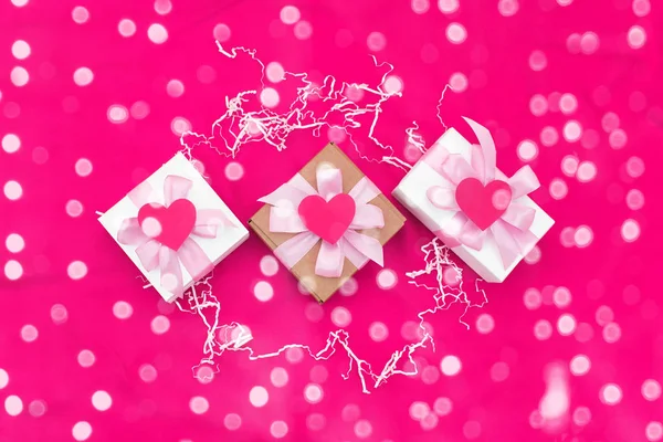 Drei Geschenkboxen gebunden mit satinfarbenem Band auf rotem Hintergrund ein rotes Herz. — Stockfoto
