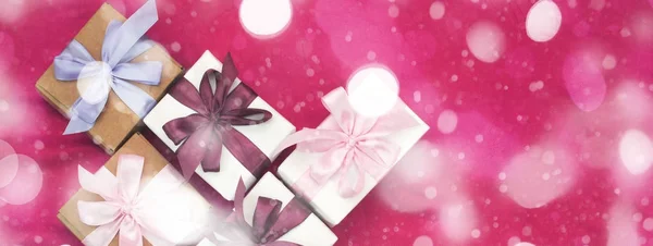 Banner gift boxes tied with satin coloured ribbon on a pink background a Red heart.