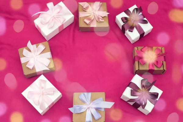 Подарункові коробки прив'язані атласною стрічкою на рожевому фоні . — стокове фото