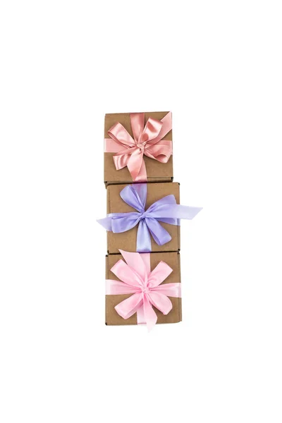 Três caixas festivas com presentes amarrados com fita de cetim em um fundo branco . — Fotografia de Stock