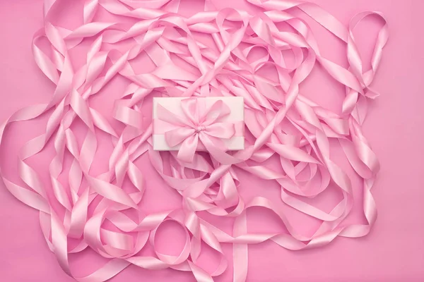 핑크 색상의 장식 새틴 리본의 코일의 배경에 선물 상자. — 스톡 사진