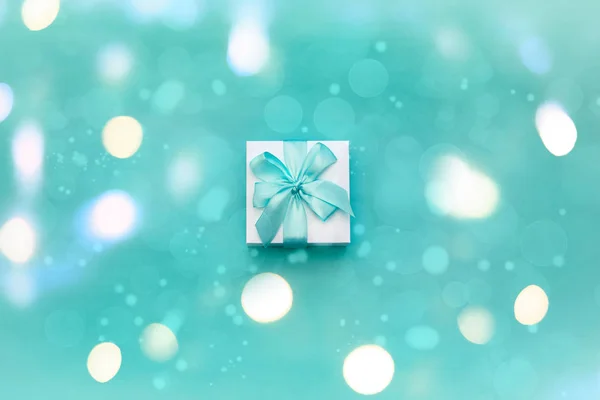 Gift box decorated with a satin ribbon on a blue background. — Stock Photo, Image