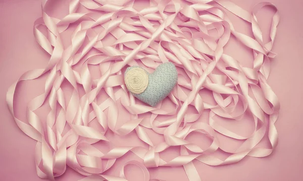Tekstylne serca na tle cewki dekoracyjne wstążki satynowe, kolor różowy. — Zdjęcie stockowe
