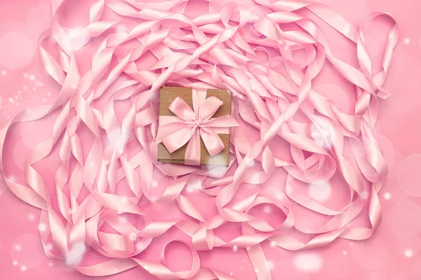 Vakken met giften op de achtergrond van een spoel van decoratieve satijnen linten van roze kleur. — Stockfoto