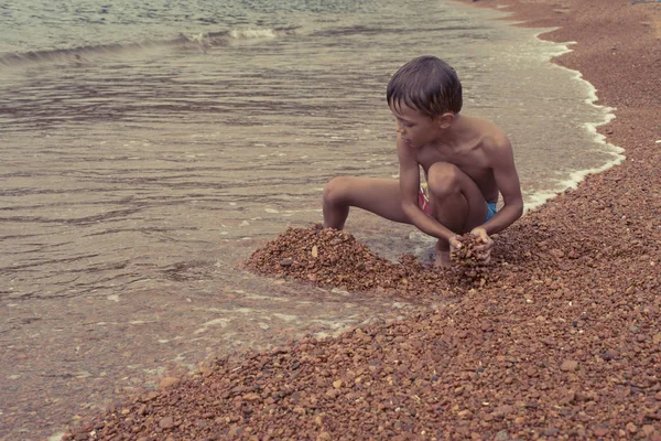 Beau garçon drôle jouant sur le bord de la mer — Photo