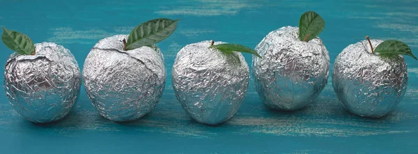 Banner Five apples in the shell foil with natural green leaves.