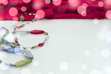 Şık kadın aksesuarları takı kutusu hediye beyaz zemin üzerine kırmızı boncuk pembe eşarp bileşimi.