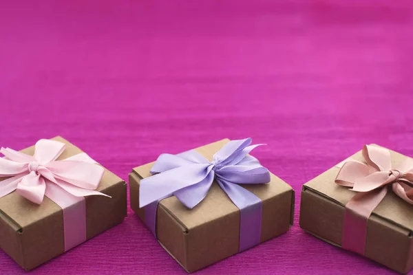 Composition festive trois boîtes Kraft avec des cadeaux sur fond rose vif . — Photo