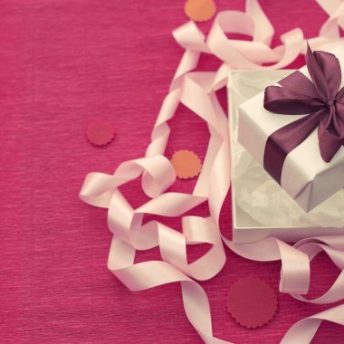 Parlak pembe bir arka plan üzerinde hediye kutusu ile şenlikli kompozisyon.