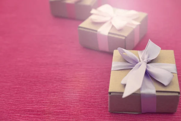 Εορταστική σύνθεση τριών Κραφτ κουτιά με δώρα σε φωτεινά ροζ φόντο. — Φωτογραφία Αρχείου