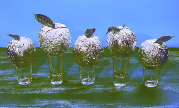 Surrealism Five apples in the shell foil with natural green leaves.