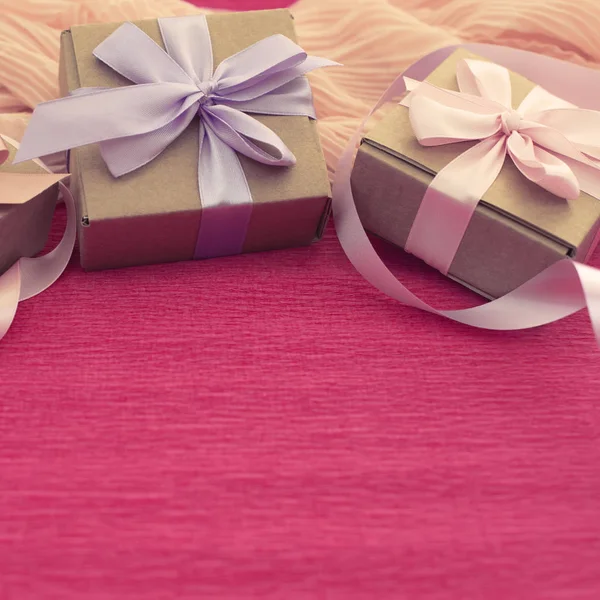 Composición festiva tres cajas de Kraft con regalos sobre fondo rosa brillante . Imagen De Stock