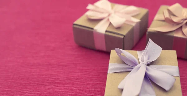 Banner εορταστική σύνθεση τριών Κραφτ κουτιά με δώρα σε φωτεινά ροζ φόντο. — Φωτογραφία Αρχείου