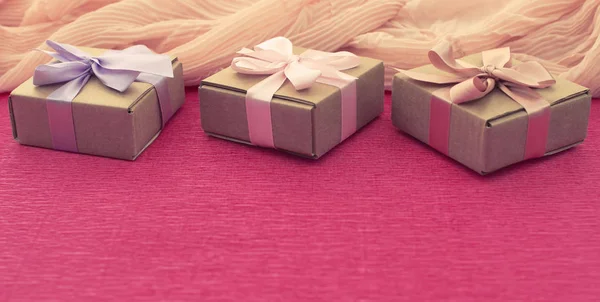 Bannière Composition festive trois boîtes Kraft avec des cadeaux sur fond rose vif . — Photo