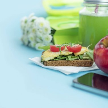 Sağlıklı vejetaryen kahvaltı. Sandviç tahıl ekmek tofu peyniri, detoks güler yüzlü, kabak çekirdeği, cherry domates, doğal çiçek, mavi arka plan, defter. Öğle yemeği için çorba ile öğle yemeği kutusu