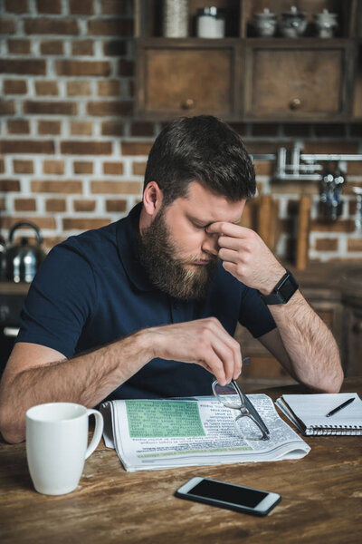 tired man with newspaper on table