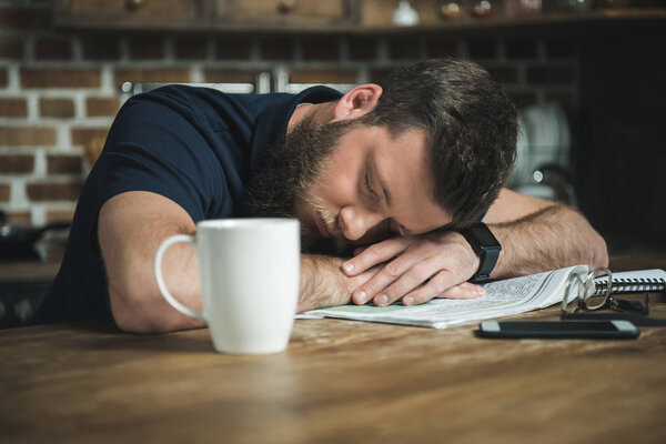 tired man with newspaper on table