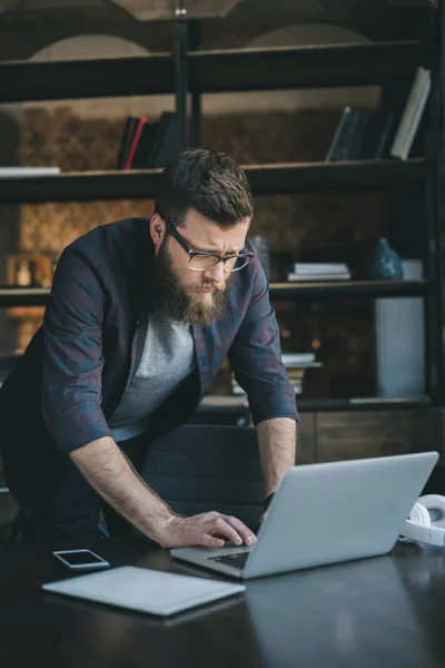Bearded man using laptop at home — Stock Photo, Image
