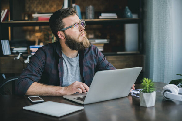 pensive bearded man typing on laptop
