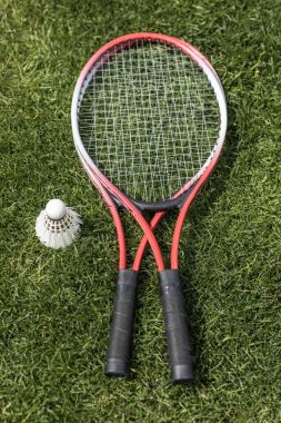 badminton rackets with shuttlecock on grass field clipart