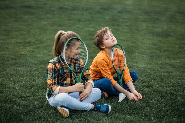 Frères et sœurs fatigués avec raquettes de badminton — Photo