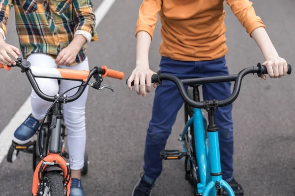 Случайные дети катаются на велосипедах по улице — стоковое фото
