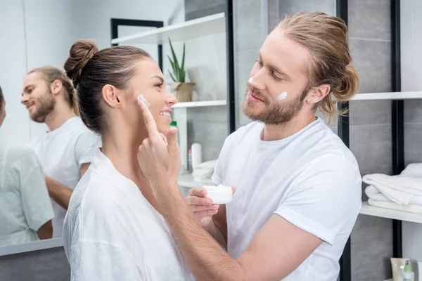 Pareja aplicando crema facial —  Fotos de Stock