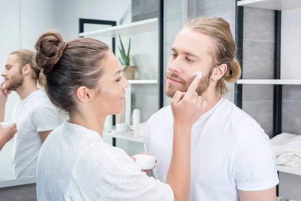Woman applying cream at husband — Stock Photo, Image