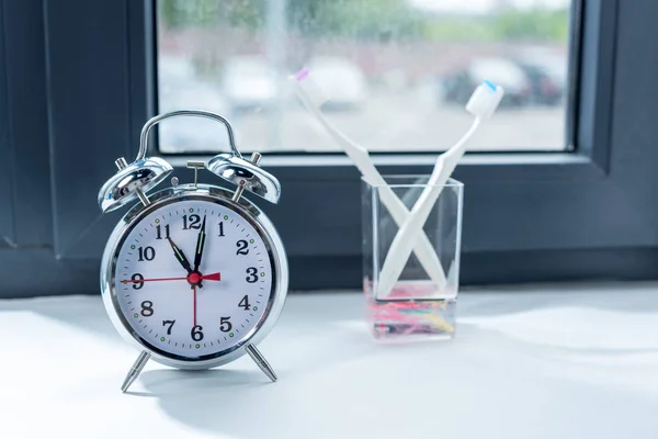 Alarm clock and toothbrushes in glass 3 — Stock Photo, Image