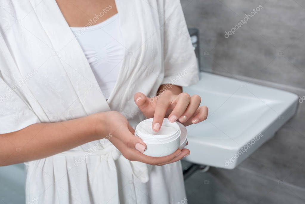 woman holding face cream