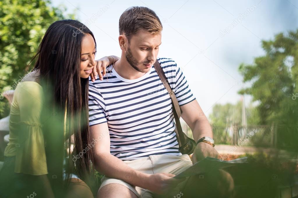 Multiethnic couple of tourists with map