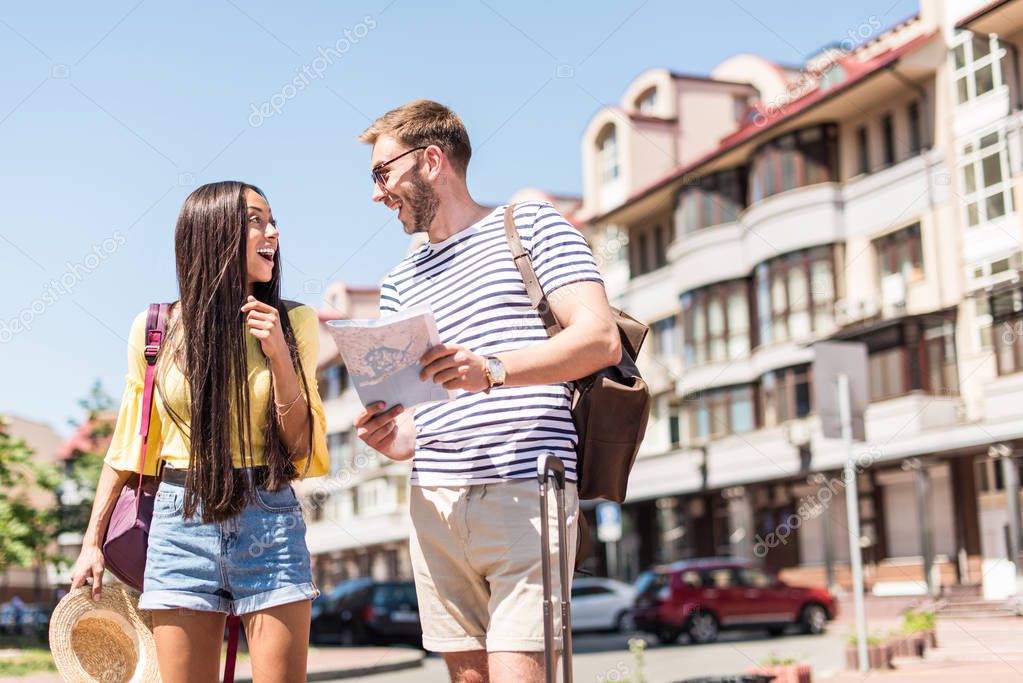 Multiethnic couple of tourists with map
