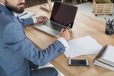 İşyerinde kağıtlarla oturan işadamı