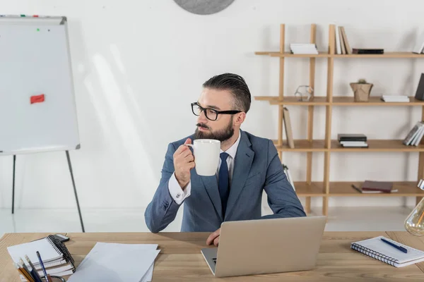 Affärsman med kaffekopp på arbetsplatsen — Gratis stockfoto