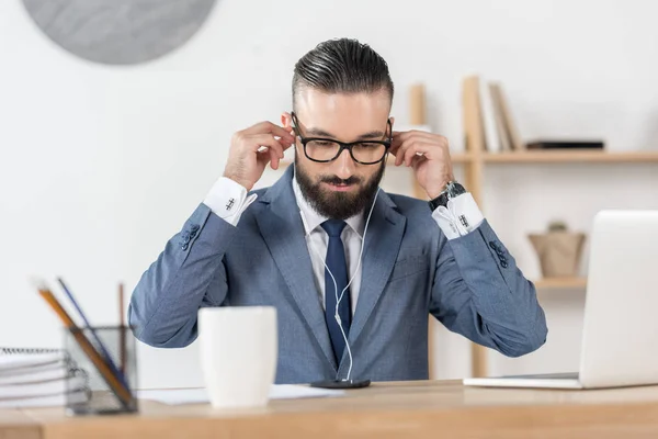 Homem de negócios em fones de ouvido no local de trabalho — Fotografia de Stock