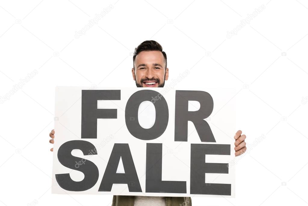 Smiling man holding for sale banner in hands and looking at camera isolated on white