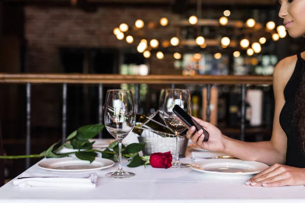 Woman using smartphone in restaurant — Stock Photo, Image
