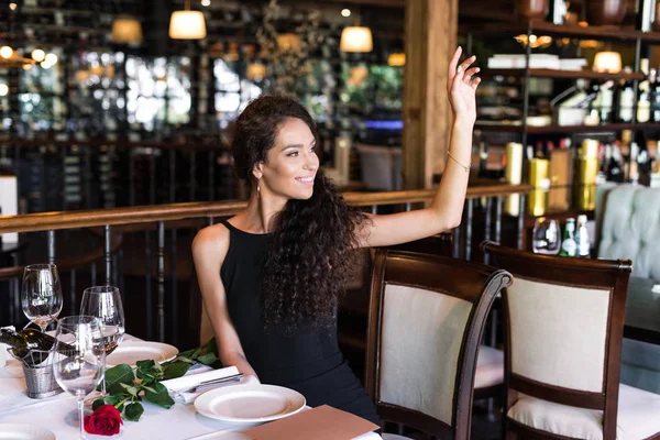 Женщина с поднятой рукой в ресторане — стоковое фото