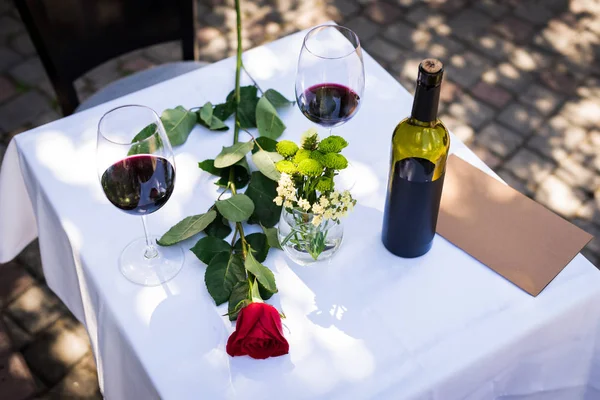 Růžový květ s vínem u stolu v restauraci — Stock fotografie