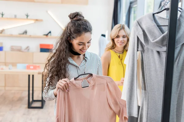 Mujeres eligiendo ropa en sala de exposición — Foto de Stock