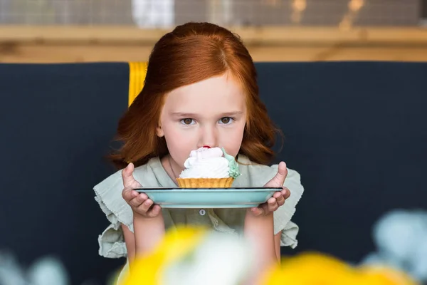 Flicka äter cupcake i café — Stockfoto