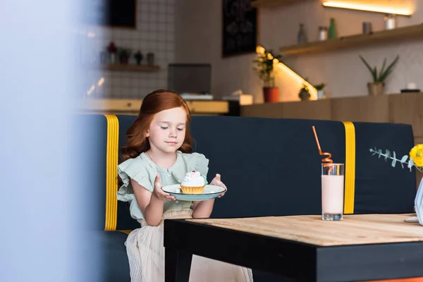 Girl eating cupcake in cafe — Free Stock Photo