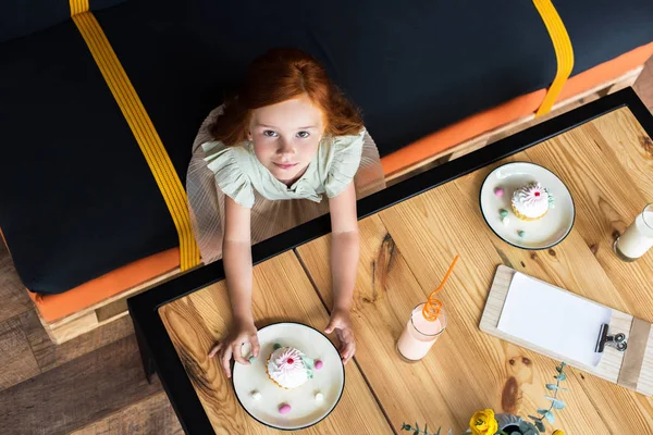 Girl eating cupcake in cafe — Free Stock Photo