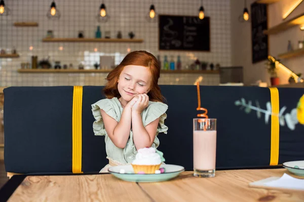 Dívka jíst cukroví v kavárně — Stock fotografie