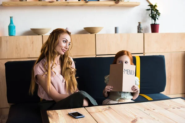 Mother and daughter reading menu in cafe — Stock Photo, Image