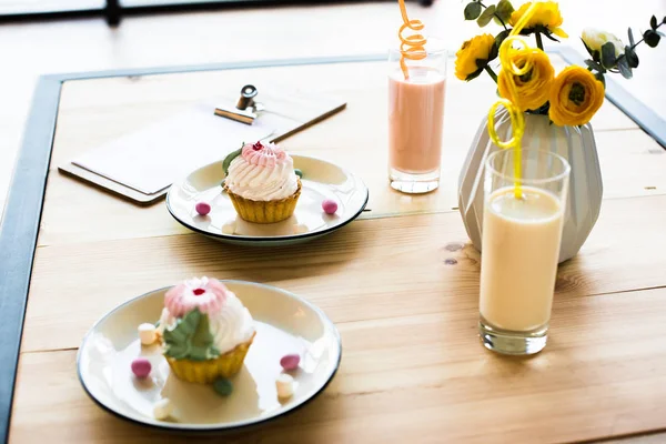 Milkshakes and cupcakes on table — Stock Photo, Image