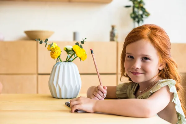 テーブルで図面の赤毛の女の子 — ストック写真
