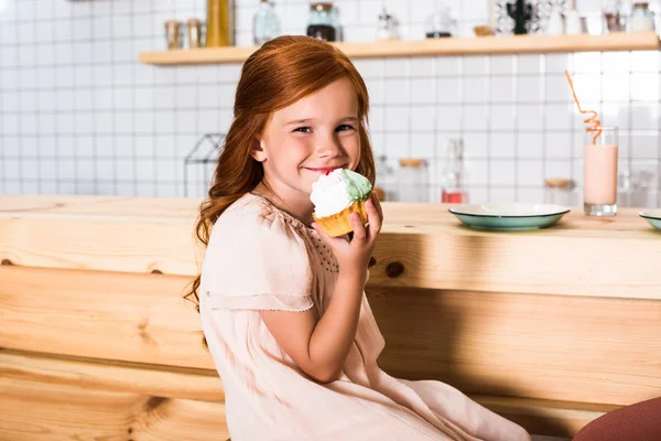 Flicka äter cupcake i café — Stockfoto